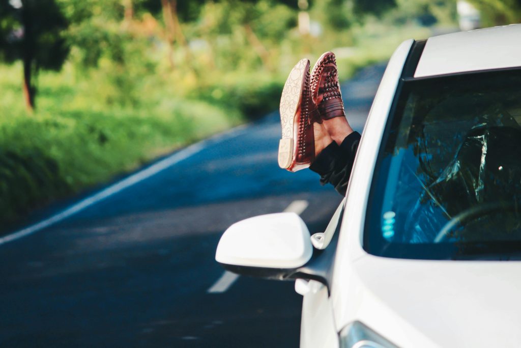 Feet hanging out of car window. 